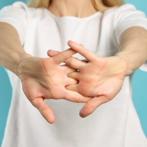 A person wearing a white shirt interlocks their fingers and extends their arms forward, with palms facing the camera, against a light blue background.